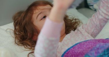 Küçük kız yatakta pelüş oyuncaklarla oynuyor. Gerçek hayatta 4K gizli görüntüler.