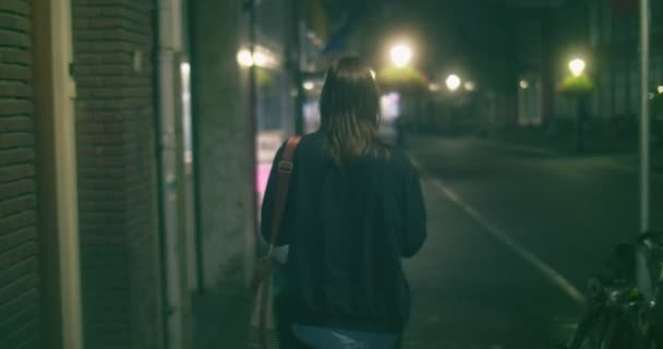 オランダのユトレヒトで夜歩く女性の後を追うリアカメラ — ストック動画