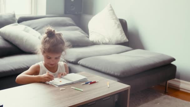 一个可爱的5岁女孩在家里 全神贯注于她的染色活动使用充满活力的标记 在舒适的环境中 她把想像力带到了一张咖啡桌上 — 图库视频影像