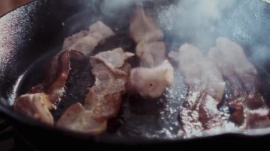 Dökme demir tavada cızırdayan domuz pastırmasının 4K görüntüsü. Yemek reklamları, yemek programları ve restoran tanıtımları için ideal..