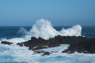ocean waves crashing on rocks during windy weather