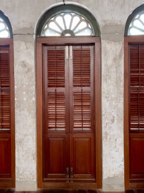 Old colonial windows with wooden frame and sunshades designed in Old Phuket town buildings, Thailand.