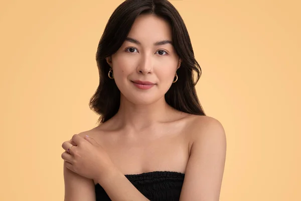 若いですアジアの女性モデル見ますカメラとタッチクリーンな裸肩にスパセッション中に黄色の背景 — ストック写真