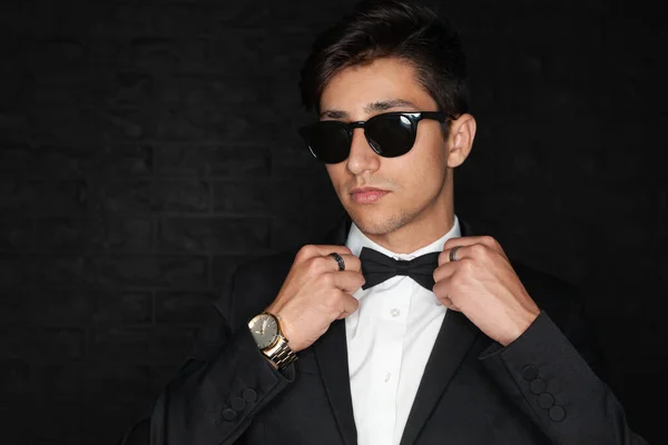Hombre Joven Con Traje Elegante Gafas Sol Elegantes Ajustando Pajarita —  Fotos de Stock