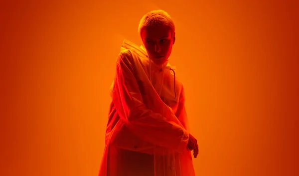 스튜디오에서 오렌지 배경을 비옷을 금발의 — 스톡 사진