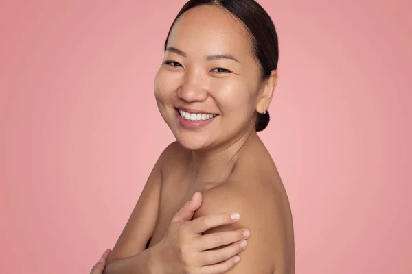 アジア民族の陽気若い女性の笑顔と感動の肩 完璧な肌と歯の笑顔とスタジオでピンクの背景に立っている間 — ストック写真