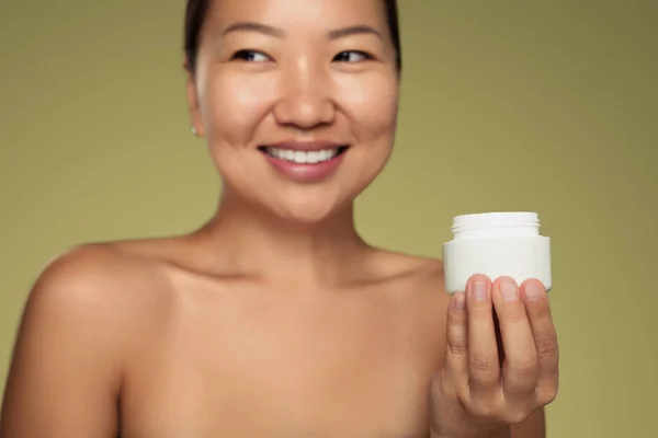 Happy Asian Female Bare Shoulders Looking Away Smile Demonstrating Jar — Stok fotoğraf