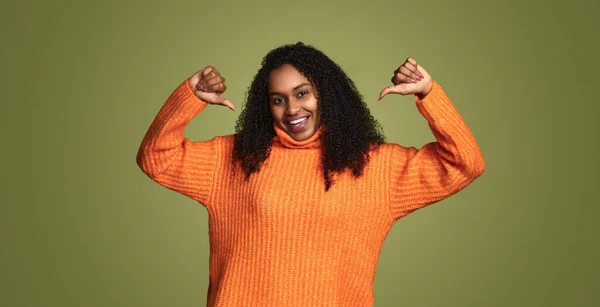 陽気若いですアフリカ系アメリカ人女性モデルとともに長いです巻き毛でニットオレンジセーター 笑顔と見てカメラで自分自身を指している間緑の背景 — ストック写真