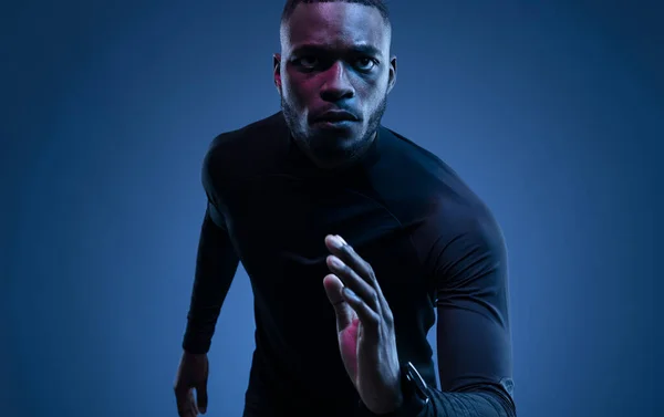 大胡子的非洲裔美国男子短跑运动员 身穿运动服 在蓝色的背景下跑开了 — 图库照片