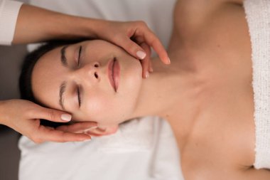 Güzellik salonundaki spa seansında havluya sarılı vaziyette kanepeye uzanan isimsiz kadın terapistin yüzü.