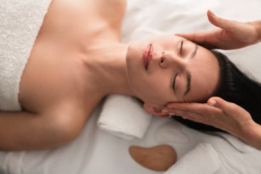 Genç kadın terapistin yüksek açılı masaj hastalarının baş ağrısı. Spa salonunda rahatlama ve rehabilitasyon sırasında.