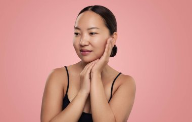 Siyah saçlı, genç, şehvetli bir kadın. Yüzüne dokunuyor ve stüdyoda gözlerini kaçırıyor.