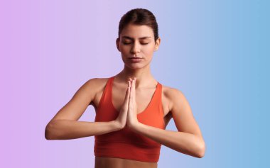 Genç, sakin, siyah saçlı, aktif giyimli, gözleri kapalı meditasyon yapan, yoga yaparken arka planda iki farklı renkte yoga yapan İspanyol kadın mankeni.