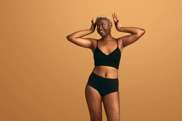 自信快乐的年轻非洲裔美国人 身材模特 穿着黑色内裤 在米色工作室里开心地笑着 望着远方 — 图库照片