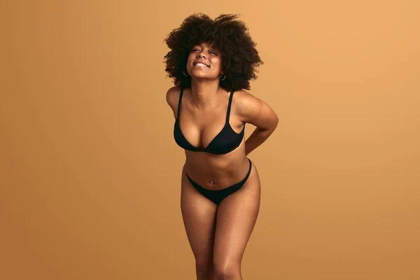 Foto de Happy beautiful African American Girl with wild curly hair and  wearing underwear in studio with a gray background do Stock