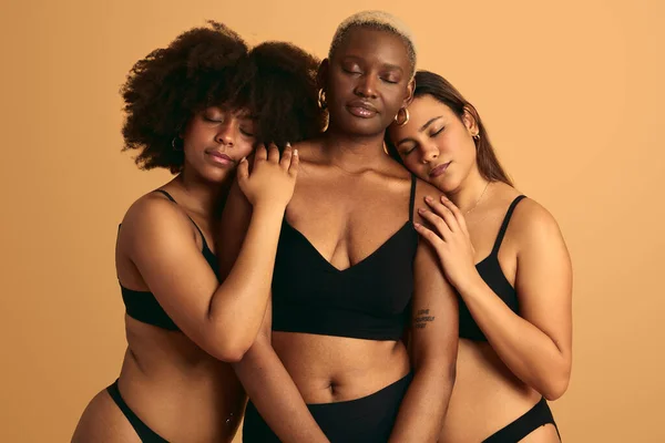 Tender Multietniska Flickvänner Svarta Underkläder Kramas Försiktigt Mot Orange Bakgrund — Stockfoto