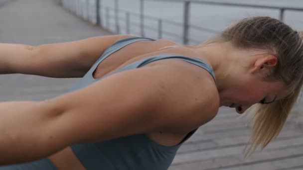 ダンベルを屋外で行使し トリップ筋肉を訓練する運動可愛い女性の閉鎖ショット 重い重みを持つスポーティ女性ポンプ手 — ストック動画