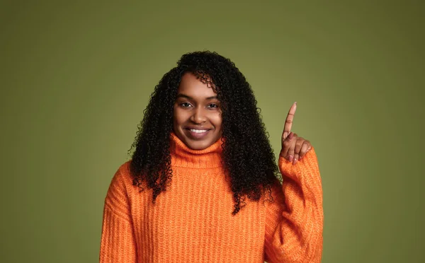 身穿橙色毛衣卷发的快乐的非洲裔美国女性一边微笑着 一边在绿色背景下看着相机 一边指指点点自己 — 图库照片