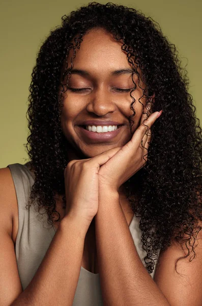 乐观的非洲裔美国女性 卷曲的头发 微笑着 对着绿色背景闭上了眼睛 自然美和护肤概念 — 图库照片