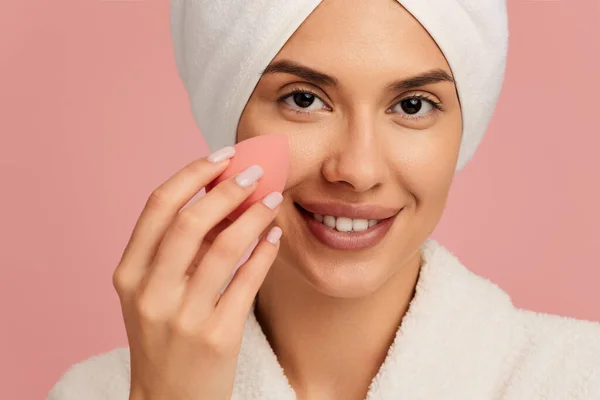 年轻快乐的女性 头戴毛巾 面颊抹粉底 粉红衬垫 看着相机 — 图库照片