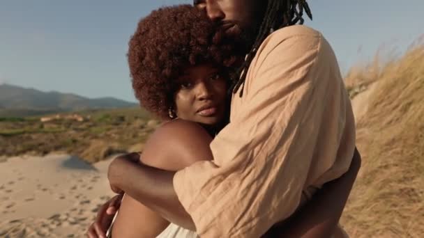 日落时黑人男子拥抱美丽的非洲女子的衣服 情爱之间的时尚和结合的概念 深色皮肤的男人拥抱着他的女朋友表示关心和保护 — 图库视频影像
