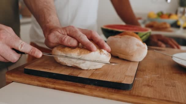 Κοντινό Πλάνο Αρσενικών Χεριών Που Κόβουν Ψωμάκι Μαχαίρι Στην Κουζίνα — Αρχείο Βίντεο