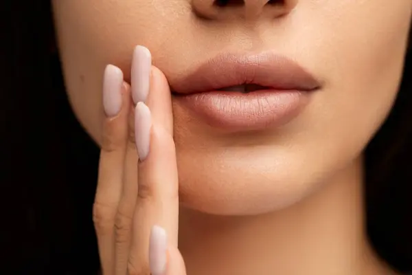 在深色背景下的护肤过程中 用修剪过的手指和凝胶在靠近张开的嘴唇处触摸面颊时对匿名女性进行的护肤 — 图库照片
