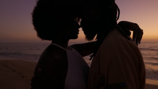 当一对黑人夫妇在令人叹为观止的海洋日落背景下为了一个浪漫的吻而逐渐走近时 激情就燃起了 — 图库视频影像