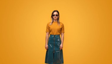 Sarı arka plan karşısında dururken boyun dokunmadan trendy cyberpunk kıyafeti tam uzunlukta genç kadın
