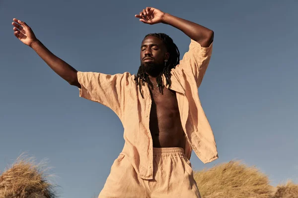 Tenang Pria Afrika Dengan Gimbal Mengenakan Pakaian Krem Mengangkat Tangan — Stok Foto