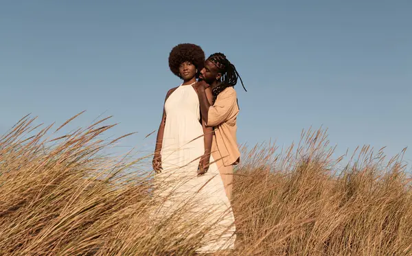 在阳光灿烂的日子里 全身上下站在干燥的田野里 头顶着无云的天空 满身金发的非洲年轻人从背后拥抱着身穿白衣的女朋友 — 图库照片