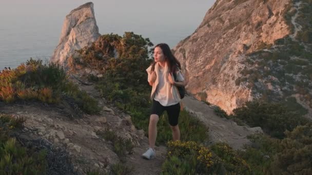 一个年轻女子背着背包爬山 欣赏日落 停下来凝视着地平线 呼吸新鲜空气的慢镜头 — 图库视频影像
