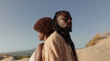 Sırt sırta duran Afro ve rastalı genç bir çift, siyah toplumunun birlik ve bağlantısını sembolize ediyor.