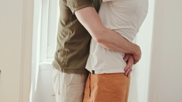 クロップトルソは 認識できない多様なゲイカップルが抱擁し 自宅で一緒にロマンチックな瞬間を共有するショット — ストック動画