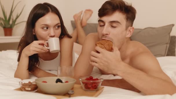 커플은 커피와 크로와상 사랑에 Basking 즐기는 남자와 침대에서 아늑한 식사를 — 비디오