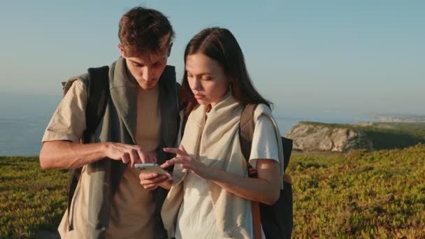 在迷人的日落远足过程中 当一对夫妇在美丽的海岸航行 用智能手机查看方向时 冒险就展开了 — 图库视频影像