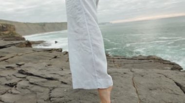Okyanus kıyısındaki kayalık bir uçurumun kenarında beyaz pantolonla dans eden kimliği belirsiz bir kadının yavaş çekimi. Çekici bacak ve kalça hareketleri ile şehvet ve kadınlığı ifade etmek