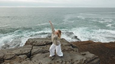 Okyanusun kıyısındaki kayalık bir uçurumda soyut bir modern dansla dans eden bir kadının tüm vücudu. Doğayla derin bir bağın dışavurumu. Çarpan dalgalara karşı gerçekten güzel bir dans.
