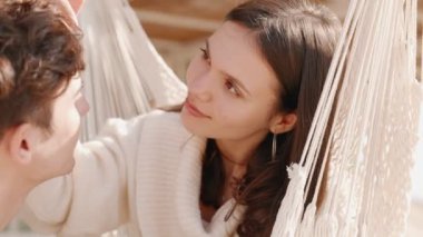 Aşık bir çift, sıcak ve güneşli bir günde hamakta kucaklaşarak romantik mutluluğun özünü yakalar.