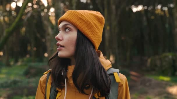 一位戴着背包和帽子的年轻女子在森林里探险 在悠闲自在的散步中品味着大自然的美丽 — 图库视频影像