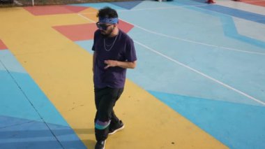 Elleri engelli genç bir adam özgürlüğü kucaklıyor, canlı bir oyun parkında hip hop dansı yapıyor, engelleri aşıyor ve çeşitliliği ve kapsayıcılığı teşvik ediyor.