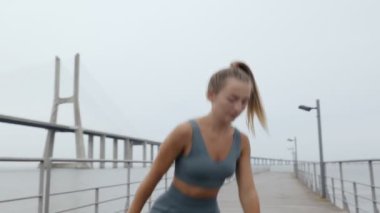 Kararlı 25 yaşındaki bir kadın bulutlu bir günde açık havada egzersiz yapar. Güç ve çeviklik için zemin dokunuşlarında ustalaşır.