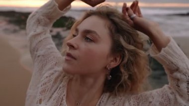 Sarışın bir kadının günbatımında plajda özgürce dans edişi, soyut dans edişi ve özgürlük ruhu..
