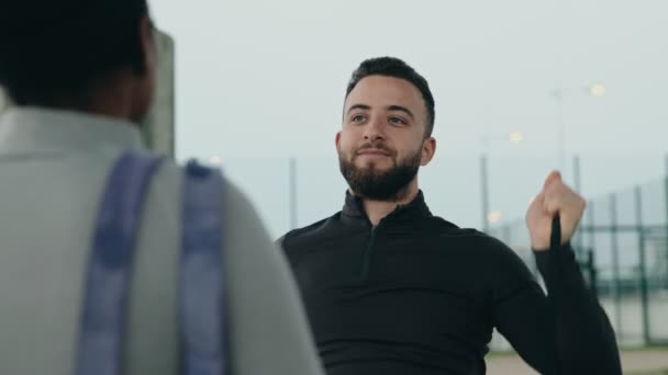 若い中東の男性はゴムバンドでトレーニングしながら 彼のフィットネスバディ テクニックを見て話す若い黒人女性 — ストック動画