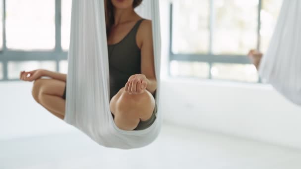 在一个明亮的瑜伽工作室里 一个女人坐在吊床上 沉思着荷花的位置 这张照片捕捉到了一段平静的时刻 她的手被有选择地聚焦在画面上 — 图库视频影像