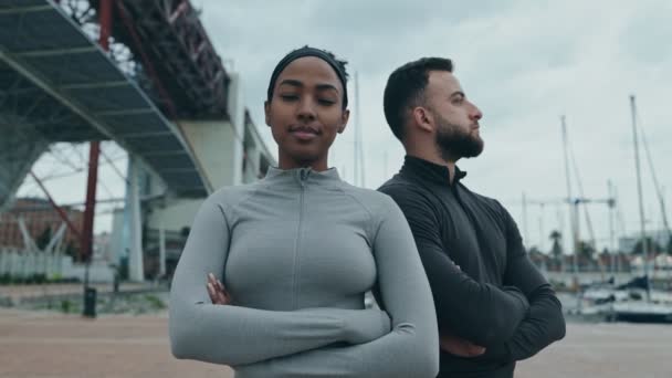 アフリカの女性と中東の男性は アウトワークアウト後の自信とチームワークを誇るアクティブウェアを身に着けている肩に立っています — ストック動画
