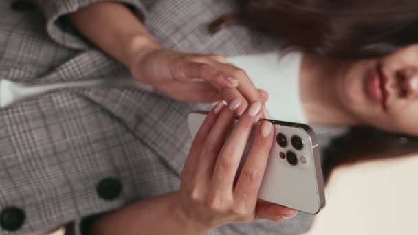 一个拿着智能手机的年轻女人的手的垂直的衣服 当她在屏幕上键入一个消息时 她的注意力集中在屏幕上 表示连通性和现代通信 — 图库视频影像