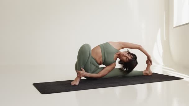 在明亮 简约的工作室空间里 一个专门的女性瑜伽运动员在向高级瑜伽姿势过渡的过程中表现出了灵活性和力量 — 图库视频影像