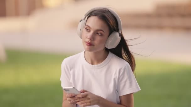 Seorang Wanita Muda Terlibat Dengan Smartphone Dan Mendengarkan Musik Menggunakan — Stok Video