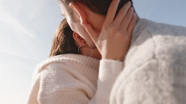 居心地の良いセーターの笑顔の若いカップルは 澄んだ空の下で抱擁しています 彼らの間の喜びと愛情は 純粋な幸福と愛を象徴しています — ストック動画